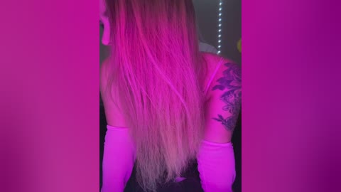 Media: A video of a woman's back, showcasing long, straight blonde hair, a tattoo sleeve on her right arm, and a pink-purple light illuminating the scene.