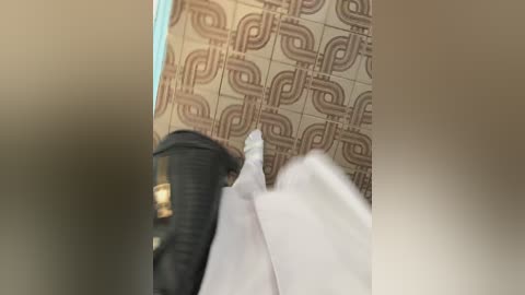 Media: A blurred video of a person in white clothing with a black backpack on a tiled floor, featuring brown geometric patterns.