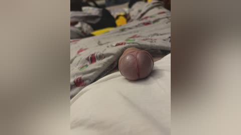 Video of a close-up of a circumcised, flaccid penis on a white sheet with a gray, patterned blanket in the background.