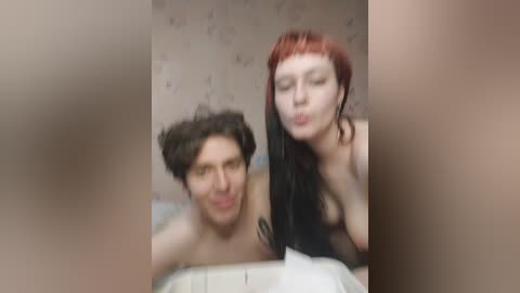 Media: A blurred video shows a shirtless man with curly hair and a woman with long, dark hair, both making kissing faces. The background features a patterned wall.