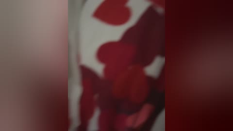 Media: A blurred, close-up video of a person wearing a red and white striped shirt with a heart-shaped design, against a similarly colored background. The image is out of focus.