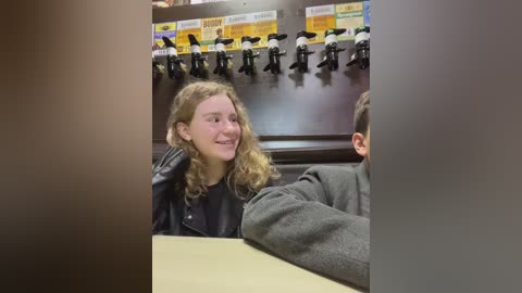 Media: A video shows a young girl with wavy hair, wearing a black leather jacket, seated at a table. Behind her, a row of beer taps is visible.