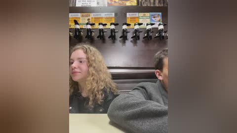 Media: Video of a blonde woman in a black jacket leaning against a wall with mounted beer taps, a man in a gray sweater visible behind her.