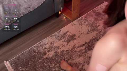 Video of a bedroom showing a bed with a grey quilt, wooden floor, and a person's foot in a brown sock, with a digital health tracker app interface in the top left corner.