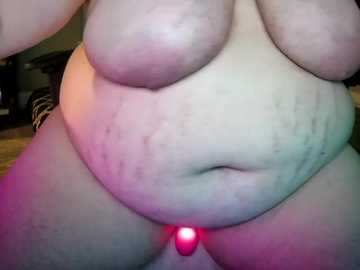 Video of a large, pale-skinned, naked woman with sagging breasts and belly, showing stretch marks and a small, pink, glowing object near her genitals.