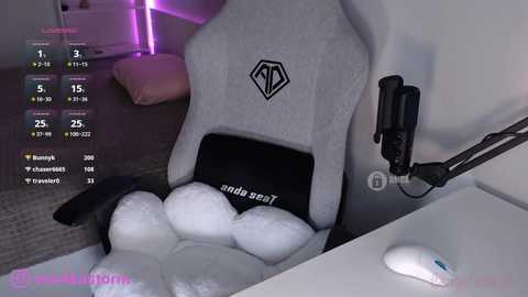 Video of a gaming setup with a gray gaming chair, black and white mousepad, and a white mouse on a desk, in a dimly lit room with purple LED lights.