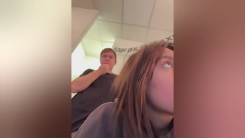 Media: Video of a woman with long brown hair and a man in a dark shirt in a salon, blurry in the background.