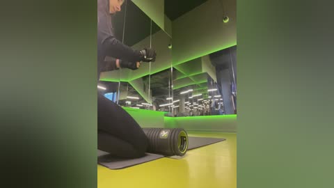 Media: Video of a person in a gym, using a black exercise mat and a foam roller. The background features modern gym equipment and lighting.