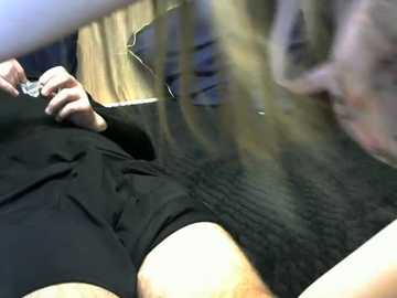 Video of a woman in a black sweater, lying on a wooden floor, with blurred faces of two other people in the background.