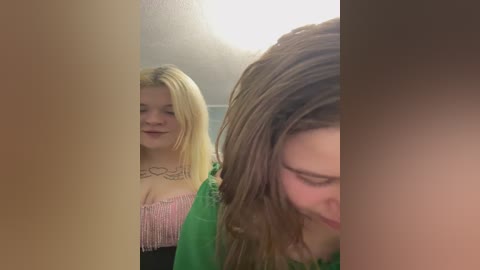 Video of two young women, one with long blonde hair in a pink fringe top, and the other with brown hair, both smiling.