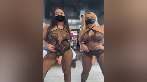 Media: Video of two women wearing black lace bodysuits, face masks, and holding dildos, in a dimly lit room with a bed and dresser in the background.