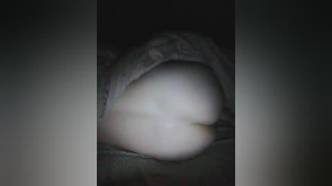 A video of a person lying on their back, covered by a blanket. The background is dark, and the subject's face is not visible.