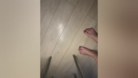 A video of a person's feet, painted red, on a beige tiled ceiling, with metal bars visible. The image captures a playful, surreal perspective.