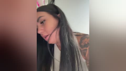 A video of a young woman with long, straight black hair, wearing a black headband and a white tank top, partially obscured by a red object.