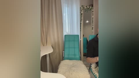 Media: Video of a modern, minimalist hospital room featuring a turquoise chair, white curtains, beige walls, and a fluffy white blanket.