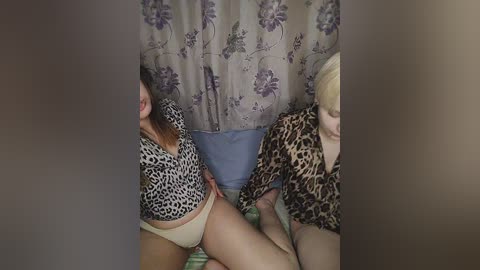 Media: A video shows two women in leopard-print tops and beige panties, with one straddling the other, in a bedroom with floral-patterned curtains.