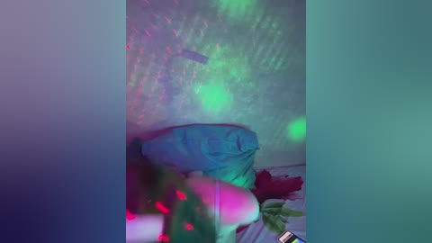Media: A video of a bed with a blue pillow and red sheets, covered in a greenish-blue light, creating a dreamy, surreal atmosphere.