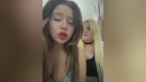 Video of two young women: one with long, wavy brown hair in a turquoise top, the other with long, straight blonde hair in a black top.