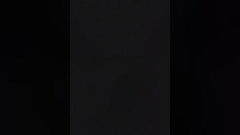 Video of a dark, shadowy vertical rectangular object against a pitch-black background, creating a stark contrast and emphasizing the object's vague, indistinct shape. The image has a minimalistic and eerie atmosphere.