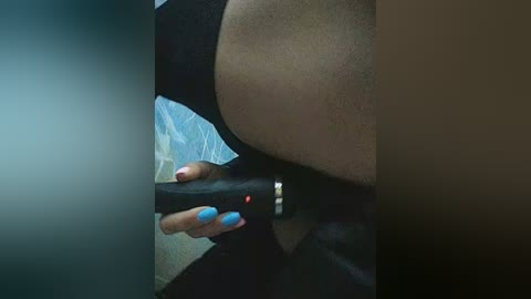 Video of a person using a black vibrator with a red light on it, positioned against their exposed buttocks. The background shows a tiled wall and a blurry, dark room.