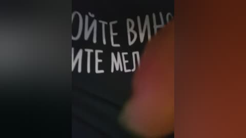 Video of a close-up of a person's face, partially blurred, with a black t-shirt bearing Cyrillic text in white. The background is dark, and the image is slightly out of focus.