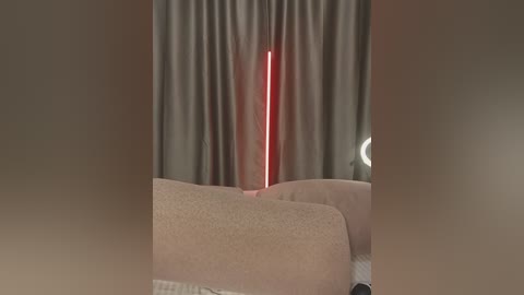 Media: A video of a modern living room featuring a tall, red LED light illuminating beige curtains and a beige couch with white lace pillows, creating a minimalist, cozy atmosphere.