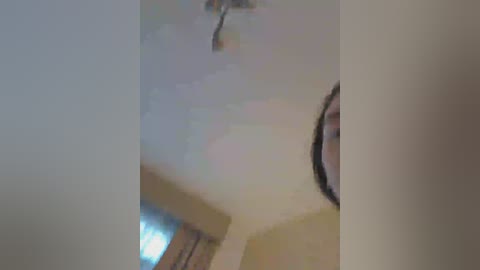 A video shows a close-up of a ceiling with a light fixture, blurred background, and a person's face partially visible on the right.