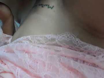 Video of a close-up of a person\u2019s neck and shoulder, featuring a tattoo of a floral design and delicate lace fabric draped over the skin, with a soft pink and white color palette.