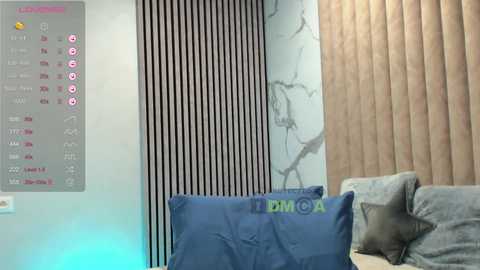 Video of a modern living room with light-colored walls, vertical black-and-white striped wallpaper, beige curtains, and a sofa with blue pillows. A digital clock with \"LIVE\" and \"FIFA\" displays is mounted on the left wall.