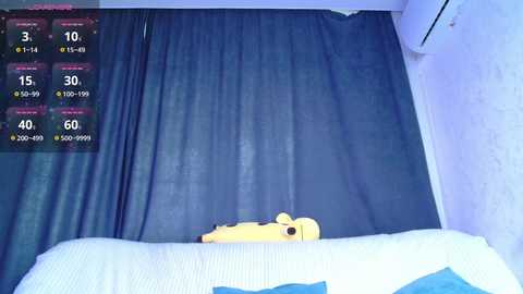 Video of a bed with a yellow bear plushie on a blue bedspread. A digital screen displays a countdown timer and temperature gauge.