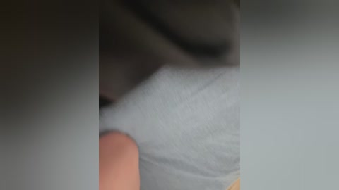 A blurred video showing a close-up of a person's arm in a light gray sleeve, with a soft, textured fabric. The background is out of focus, making the subject the central focus.