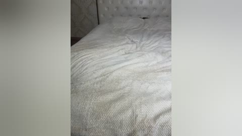 A video of a neatly made bed with white sheets and a tufted headboard in a dimly lit room. The bedding appears crisp and tidy, creating a clean, minimalist aesthetic.