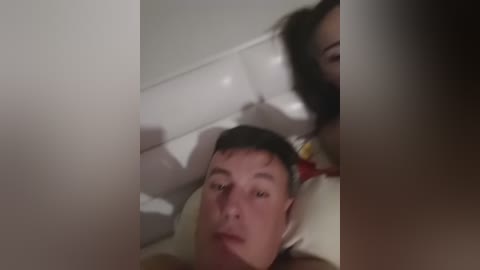 A video shows a man, lying down, with a woman leaning over him, her face partially obscured. The scene is dimly lit, creating a sense of intimacy and privacy.