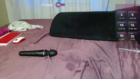 Video of a bedroom with a pink bedspread, a black vibrator on the left, and a black headboard, displaying a sex game app interface on the right.