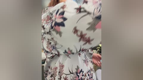 Media: A video of a person wearing a white floral dress with pink and black floral patterns, blurred background.