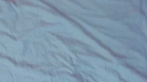 Media: Video of a single sheet of light blue fabric with subtle creases and folds, creating a soft, textured appearance. The fabric is smooth and slightly wrinkled, giving it a relaxed and informal look.