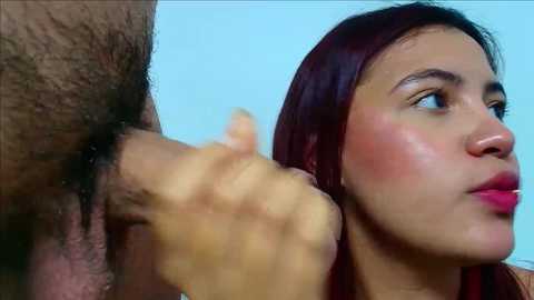 Media: A video of a young, light-skinned woman with long, dark red hair, wearing pink lipstick, being kissed passionately by a man with a hairy, circumcised penis.