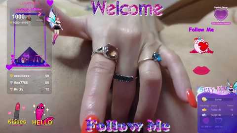Media: Video of a hand with multiple rings, including a large pink gemstone, against a blurred background. The image is overlaid with \"Welcome\" and \"Follow Me\" text, and \"Kisses\" and \"Hello\" icons.