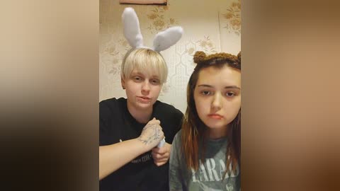 Media: A video of two young girls in a bathroom. One wears bunny ears, the other a braided headband. They have pale skin and are in casual clothes.