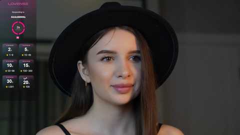 Media: Video of a young woman with long brown hair, wearing a black hat and black top, smiling softly, with a weather app overlay showing temperature and precipitation.