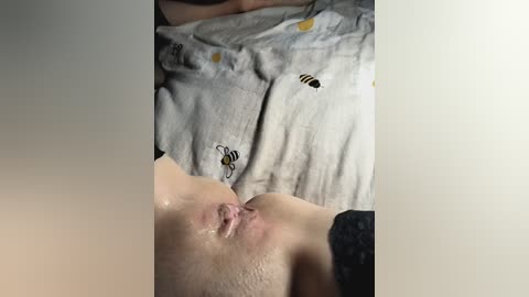 Media: A video shows a close-up of a person's face with a bee on their shirt and their exposed genitalia. The person has light skin and wears a gray shirt with bees on it.