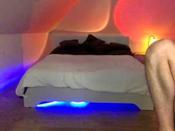 Media: Video of a minimalist bedroom with a white bed, pillows, and a soft light. The room is bathed in warm, glowing red and orange light, with a blue LED strip under the bed.