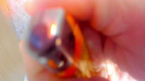 Blurry, close-up video of a person with fair skin and a visible tattoo on their arm, surrounded by a pink and orange glow, with an indistinguishable background.