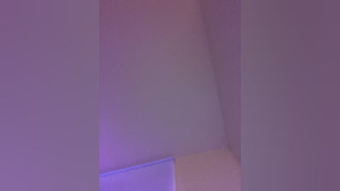 A video of an indoor corner with soft, pastel purple and blue lighting, showcasing a smooth, white wall and a beige door, creating a serene, minimalist ambiance.