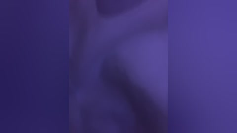 A blurred video featuring a nude, pale-skinned figure with undefined gender, standing in a dimly lit room with a purple hue, creating a mysterious and evocative atmosphere.