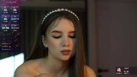 Media: Video of a young woman with long brown hair, wearing a pearl headband, and makeup, in a dimly lit room. A live stream overlay shows her stats.