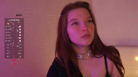 Video of a young woman with long, straight brown hair, wearing a black top and a heart-shaped choker, looking pensive against a pink-tinted wall with a \"Love Meter\" graphic.
