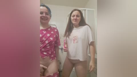 Video of two young women, one with blue hair and one with long brown hair, in pajamas. They stand in a bathroom, smiling.