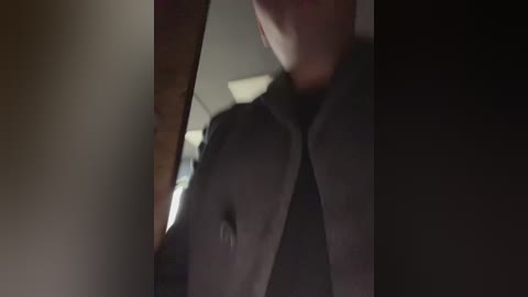 Media: A dimly lit video captures a person's upper torso in a black jacket, partially obscured by a blurred, shadowy figure in the background.