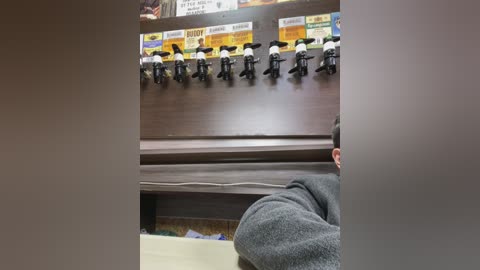 Media: Video of a man in a gray jacket, partially obscured, standing at a self-serve beer tap in a dark wooden bar.